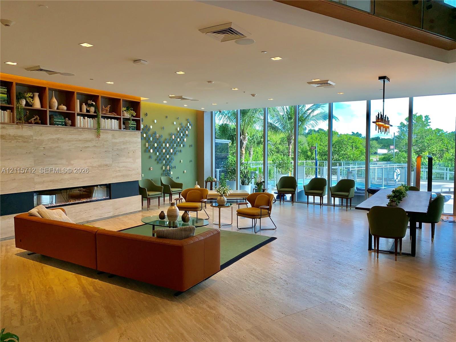 Open-concept interior featuring floor-to-ceiling glass walls, large-format stone-finish flooring, a linear built-in fireplace, and expansive built-in shelving