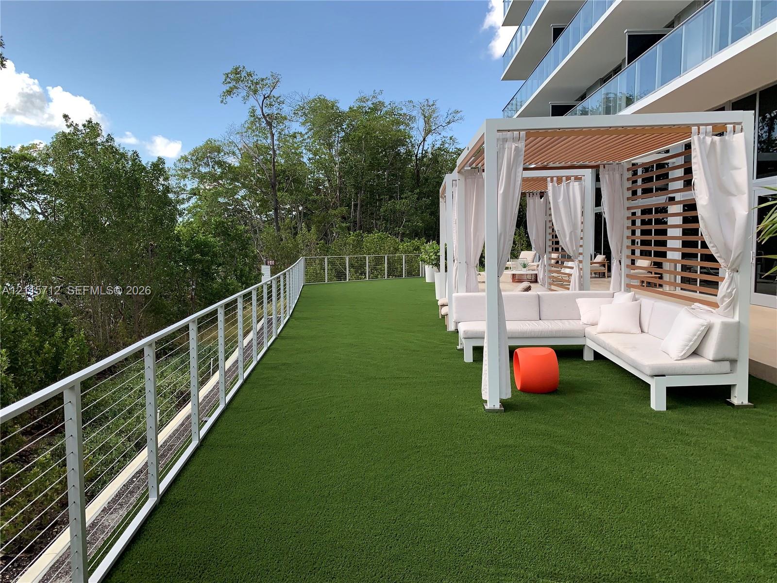 Spacious terrace featuring synthetic turf, metal cable railing, and structured wooden pergolas