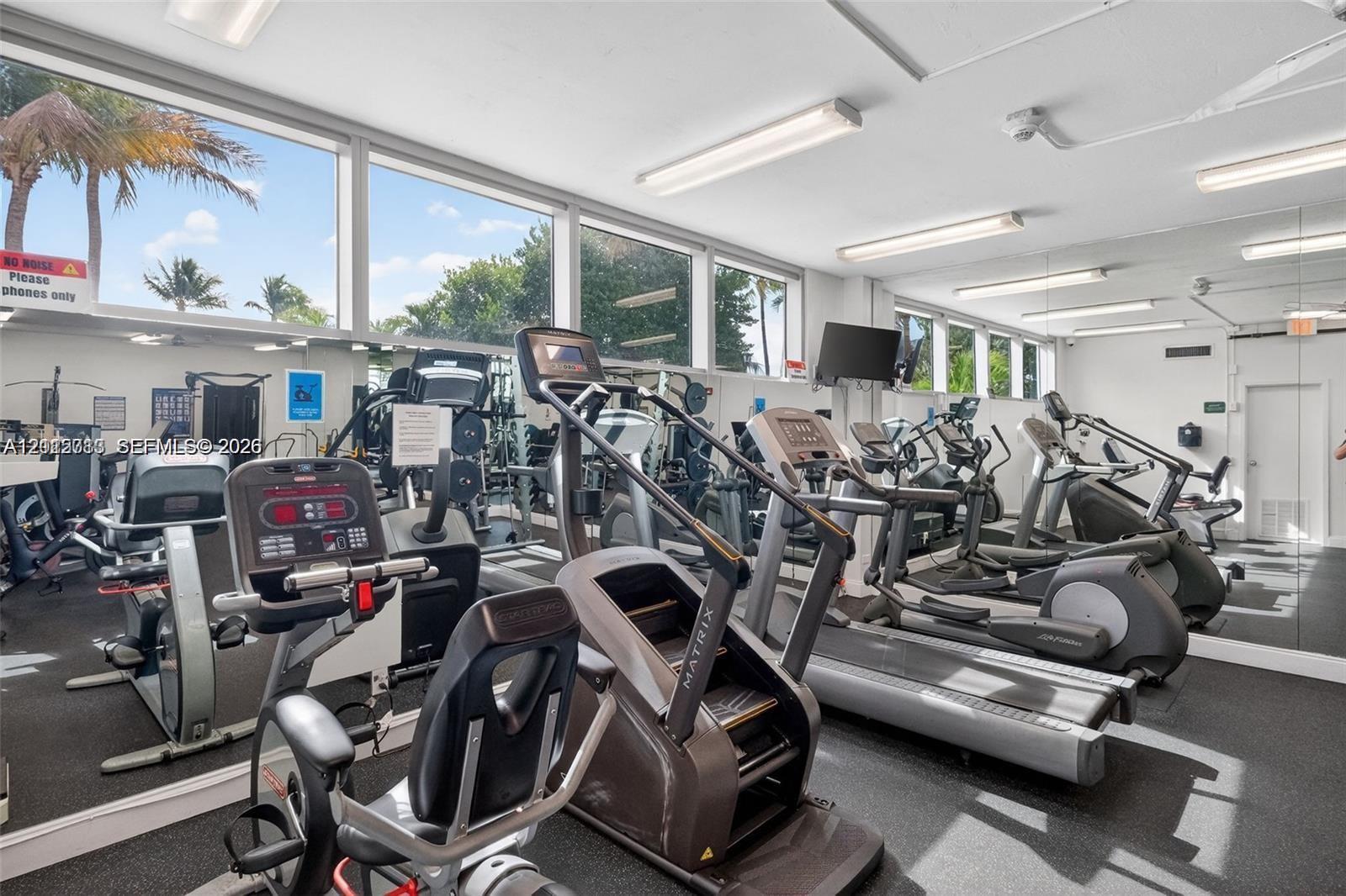 Fitness center featuring wall-to-wall mirrors, floor-to-ceiling windows, and impact-resistant flooring