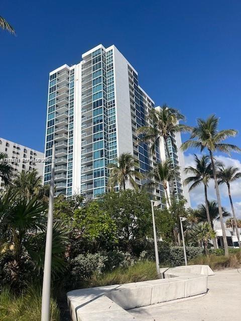 High-rise exterior featuring glass-railing balconies, floor-to-ceiling windows, and concrete architectural facade