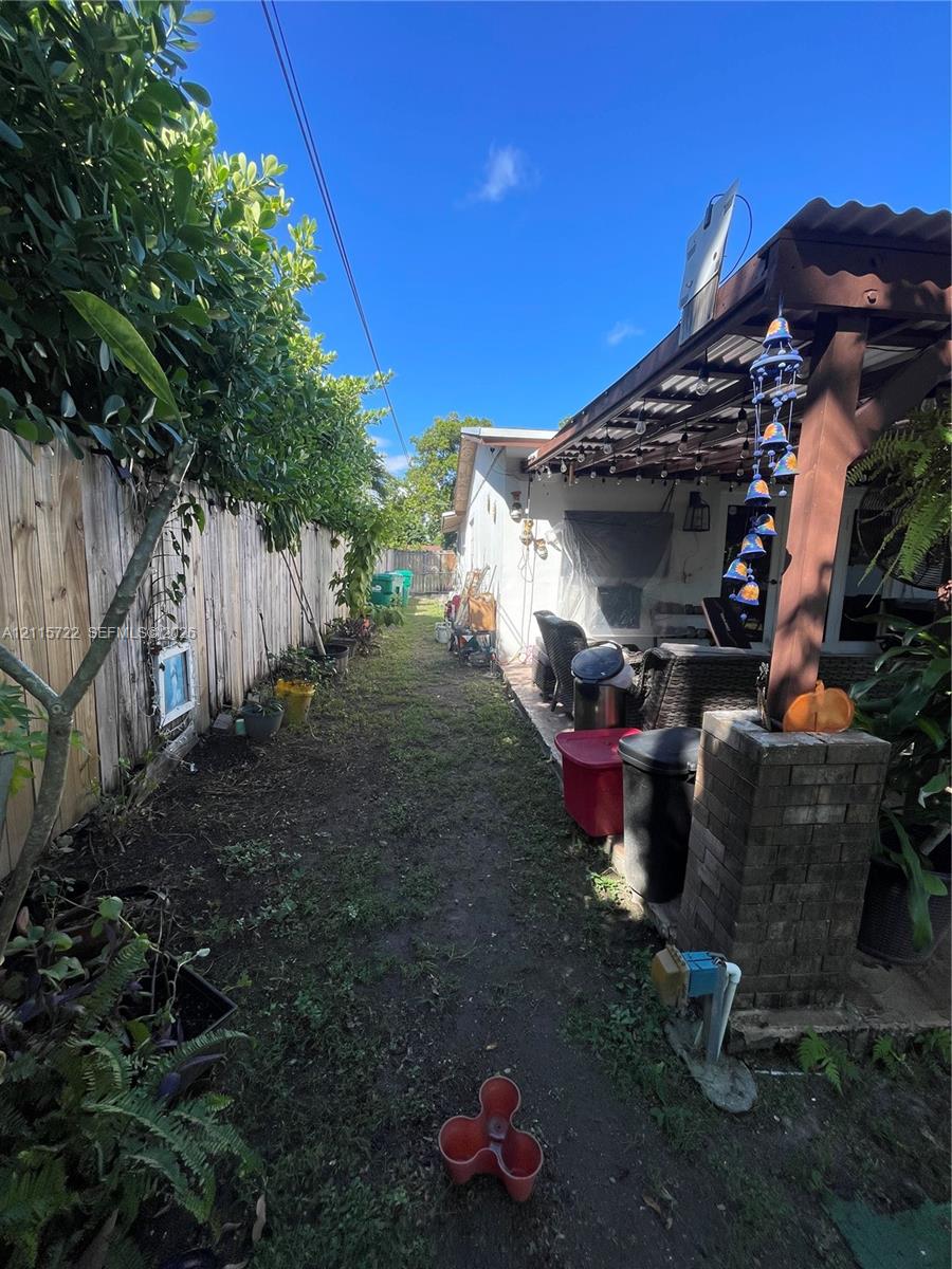 Side yard featuring a covered patio, brick masonry pillar, and wood-panel privacy fencing