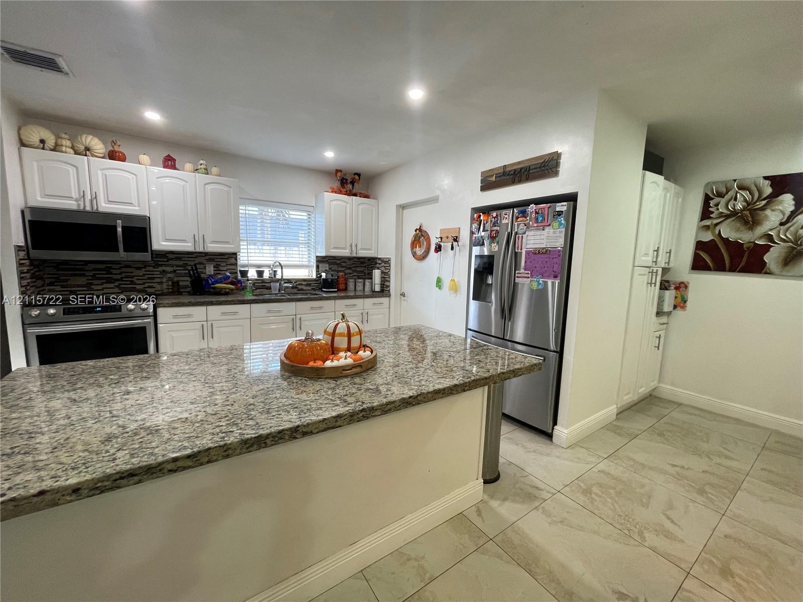 Kitchen featuring white cabinetry, stone-surface countertops, tile flooring, recessed lighting, and stainless steel appliances