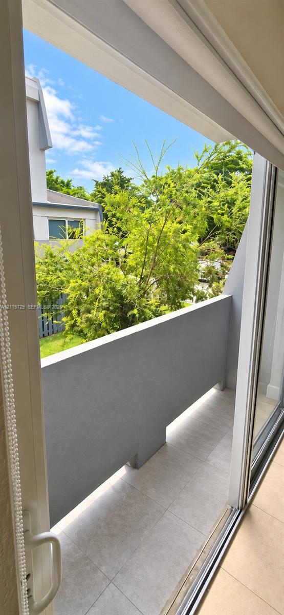 Private balcony featuring a concrete-finished floor and solid concrete railing, accessed via a sliding glass door Private balcony featuring a concrete-finished floor and solid concrete railing, accessed via a sliding glass door
