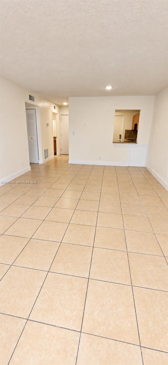 Open-concept area featuring tile flooring, smooth-finish ceilings, recessed lighting, and a pass-through opening Open-concept area featuring tile flooring, smooth-finish ceilings, recessed lighting, and a pass-through opening