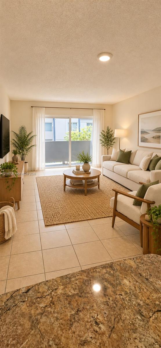 Living area featuring large-format neutral floor tile, recessed ceiling lighting, and sliding glass doors leading to an exterior balcony