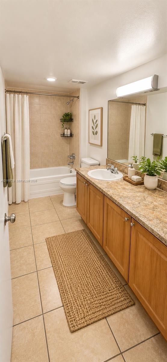Bathroom featuring a wood-finish vanity with a stone-composite countertop, an integrated oval sink, a full-width vanity mirror, and ceramic tile flooring