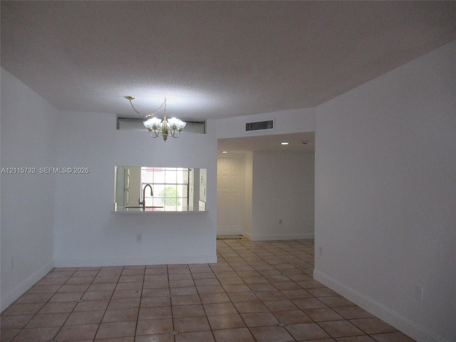 Ceramic tile flooring, multi-light hanging chandelier, and pass-through window with solid-surface counter