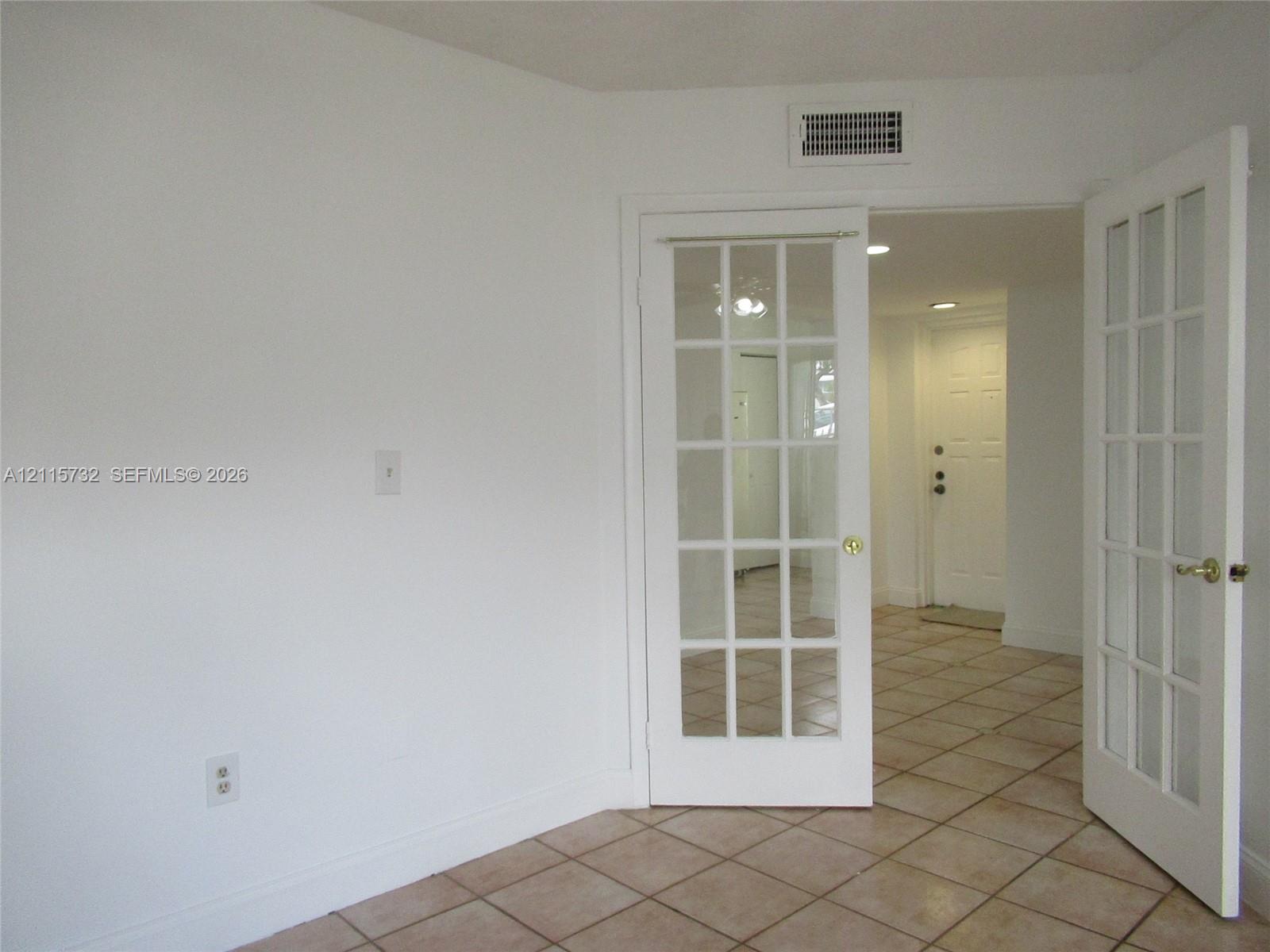 White French doors featuring multi-pane glass panels, complemented by ceramic tile flooring and recessed ceiling lighting