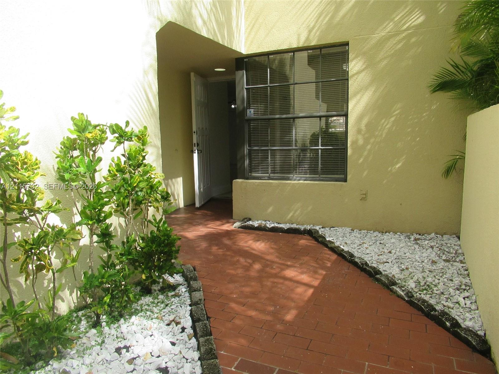 Private entrance featuring a paved brick walkway, perimeter stone landscaping, multi-pane window, and stucco exterior finish Private entrance featuring a paved brick walkway, perimeter stone landscaping, multi-pane window, and stucco exterior finish