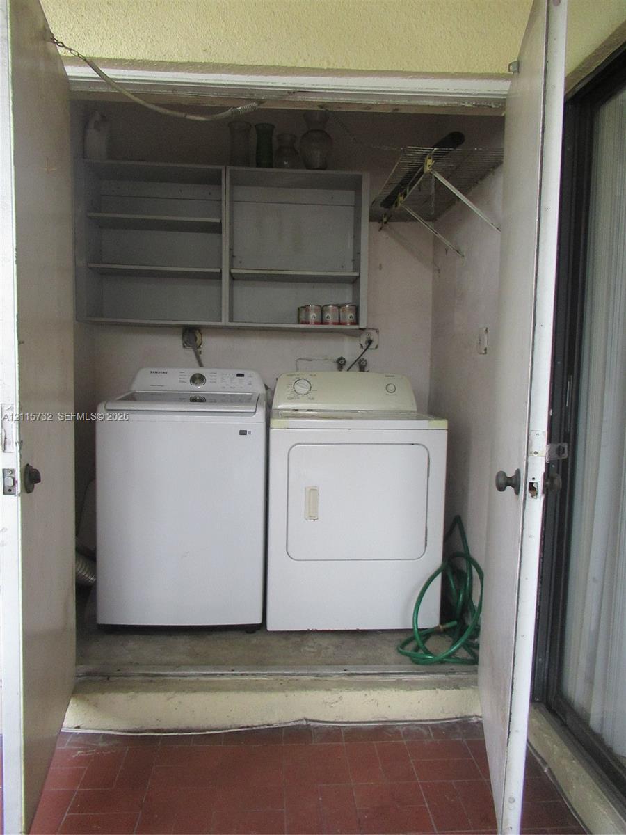 Laundry closet featuring dual bifold doors and built-in upper shelving