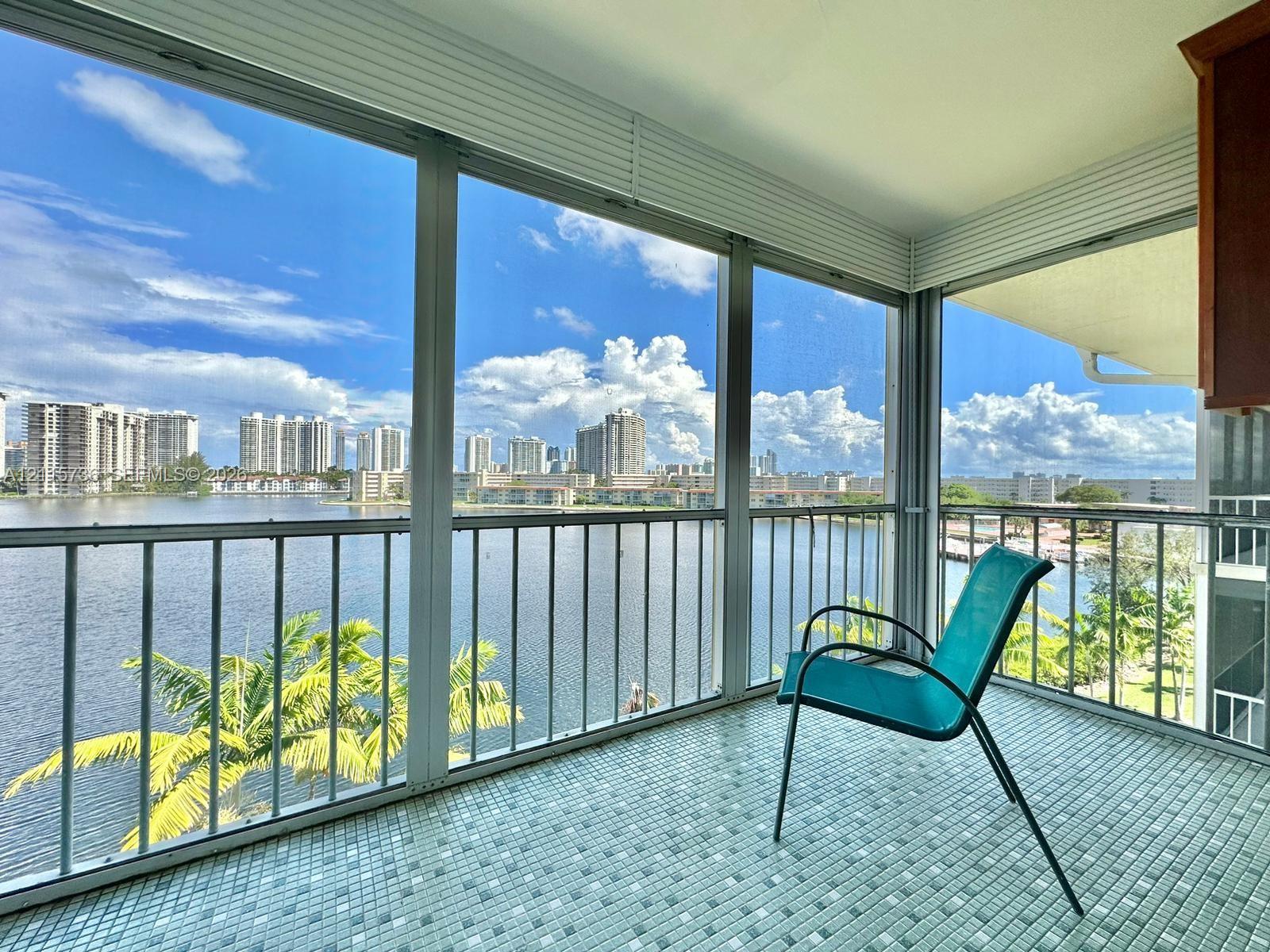 Enclosed balcony featuring floor-to-ceiling glass paneling, metal railing, and mosaic tile flooring