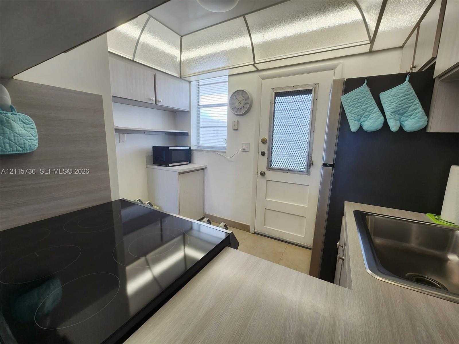 Kitchen featuring wood-finish countertops, a glass-top electric range, integrated recessed soffit lighting, and a stainless steel undermount sink