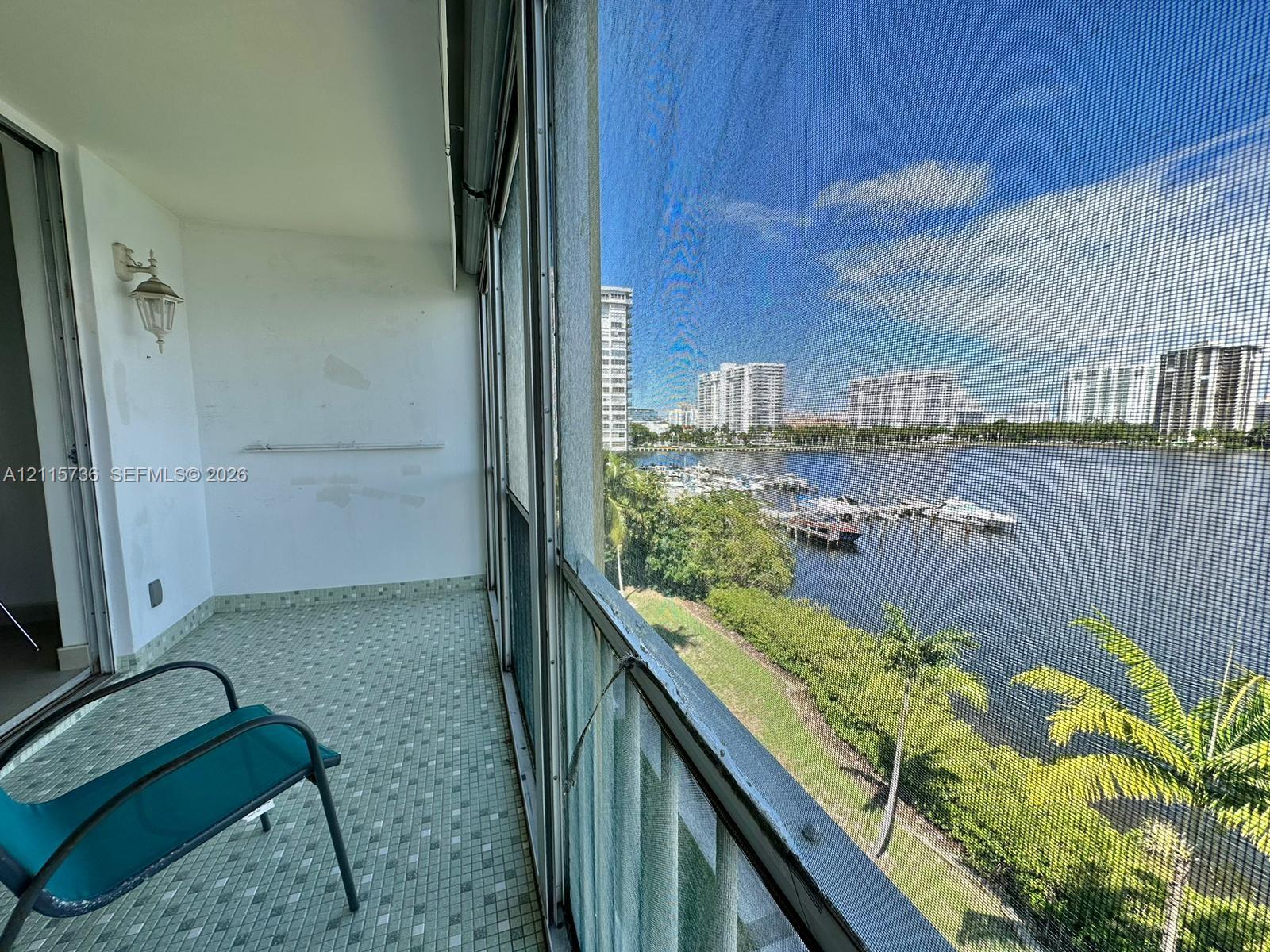 Covered balcony featuring screen enclosure, tile flooring, and wall-mounted sconce lighting