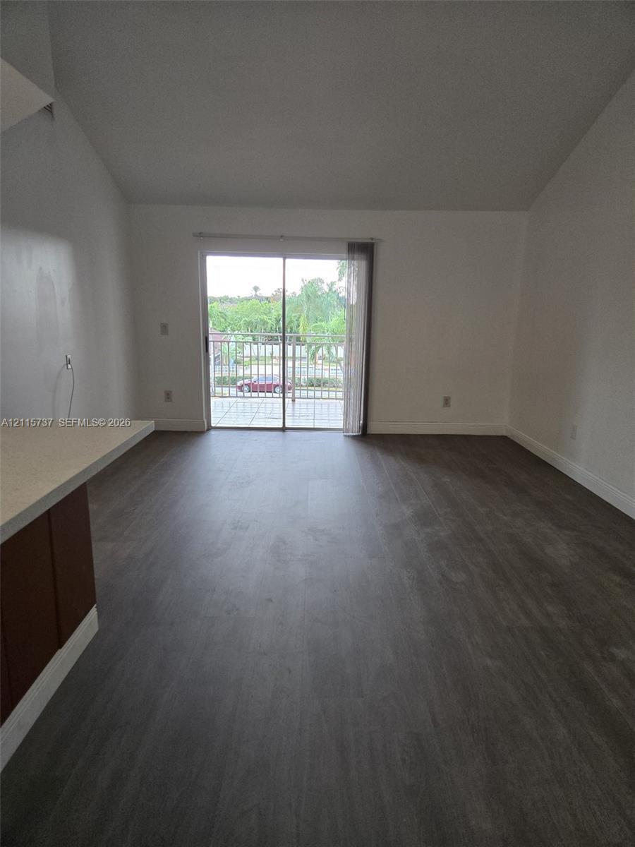 Vaulted ceilings, wood-finish flooring, and sliding glass doors opening to an exterior balcony