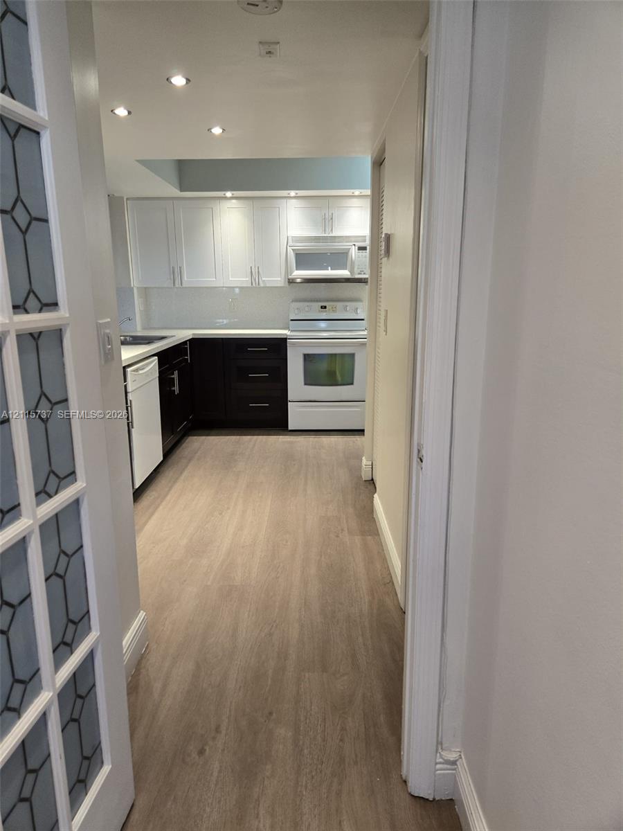 Kitchen featuring dual-tone cabinetry, wood-finish flooring, recessed lighting, and a glass-paneled entry door