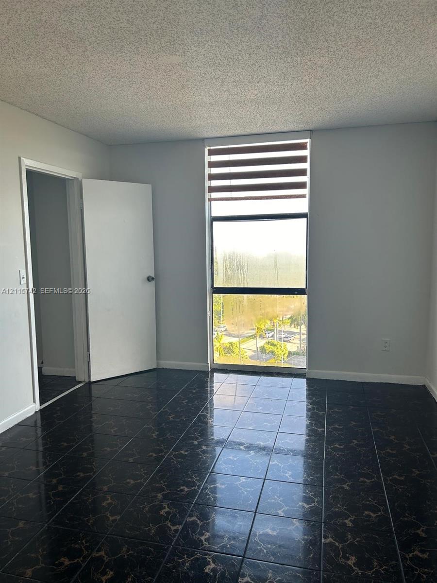 Interior space featuring large-format dark tile flooring, a floor-to-ceiling vertical window, and adjustable horizontal blinds