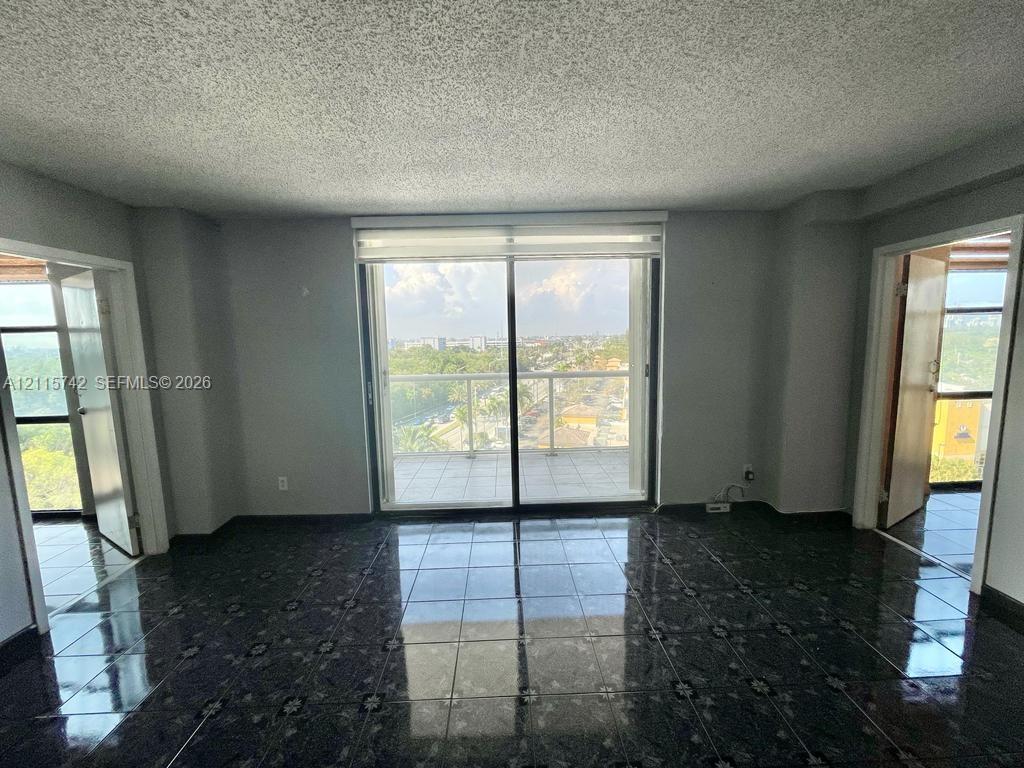 Interior space featuring large-format dark tile flooring, sliding glass doors, and a private balcony with glass railing