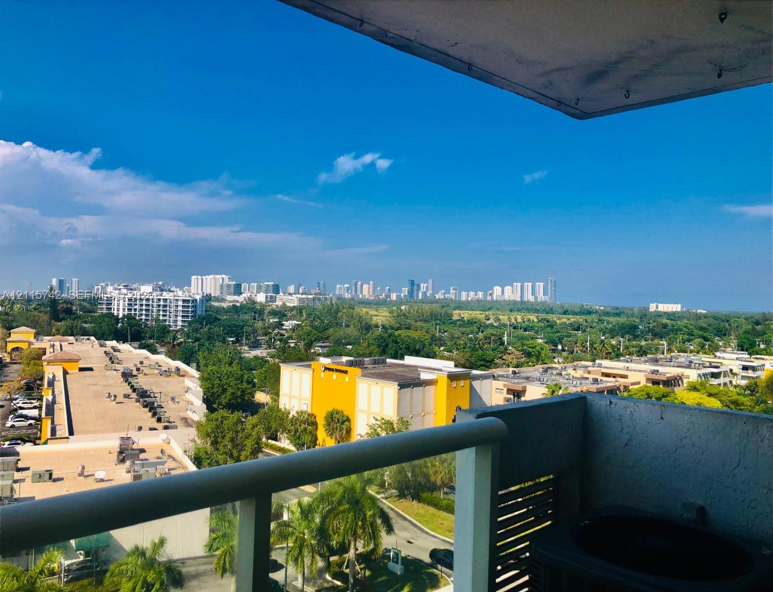 Elevated balcony with a metal railing, overlooking urban skyline and mature greenery