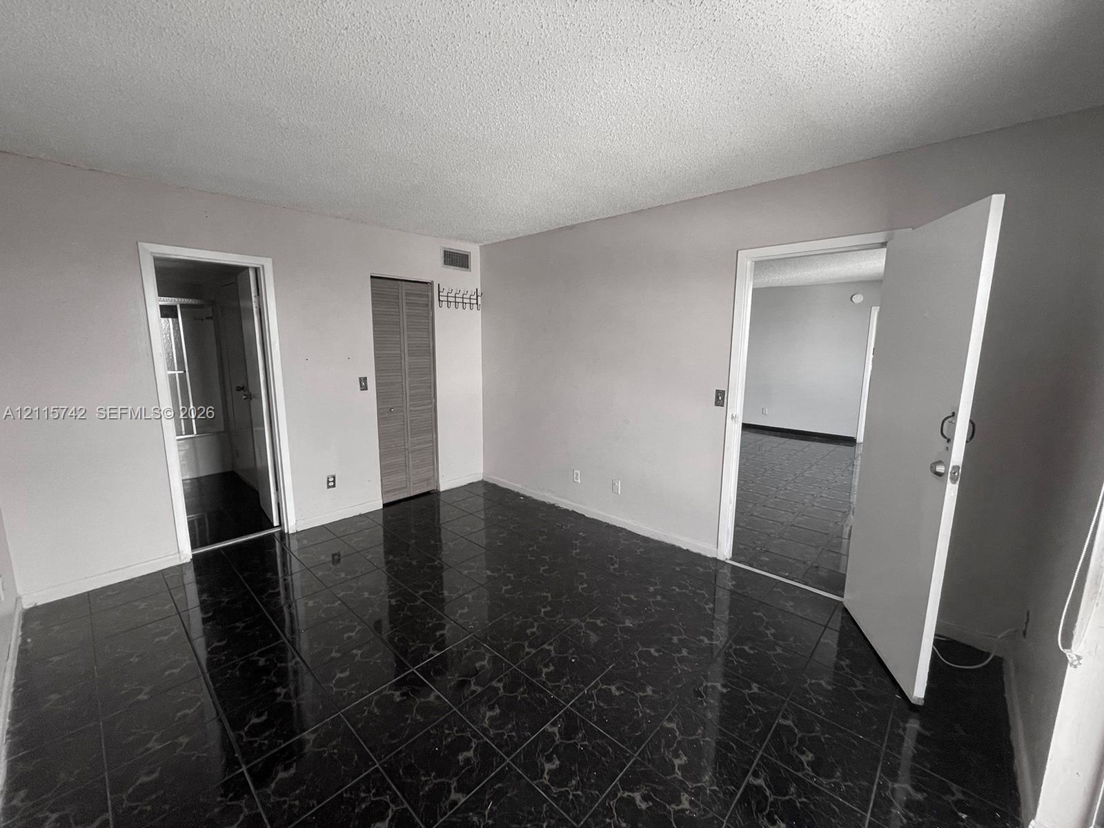 Interior space featuring dark, high-gloss tile flooring, louvered closet doors, and multiple interior doorways