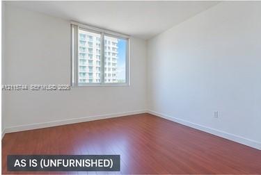 Interior space featuring wood-finish flooring, white walls, and a large window