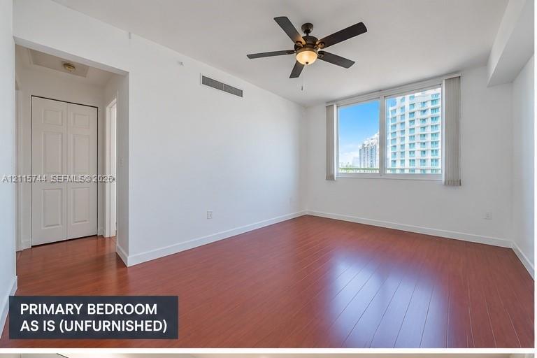 Room featuring wood-finish flooring, a ceiling fan with integrated lighting, and a closet with double-panel doors
