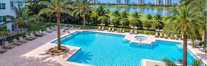 Outdoor swimming pool and spa featuring a paver deck, mature palm trees, and water-facing landscaping