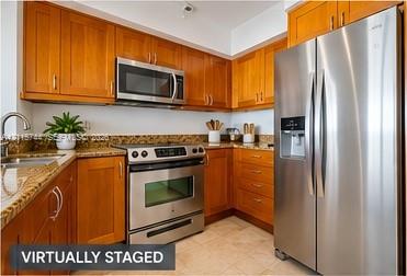 Kitchen featuring wood cabinetry, stone countertops, stone tile backsplash, stainless steel appliances, and a double-basin undermount sink with a gooseneck faucet