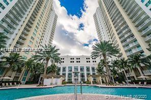 Multi-story residential complex featuring a swimming pool, paved pool deck, pergola structures, and mature palm landscaping
