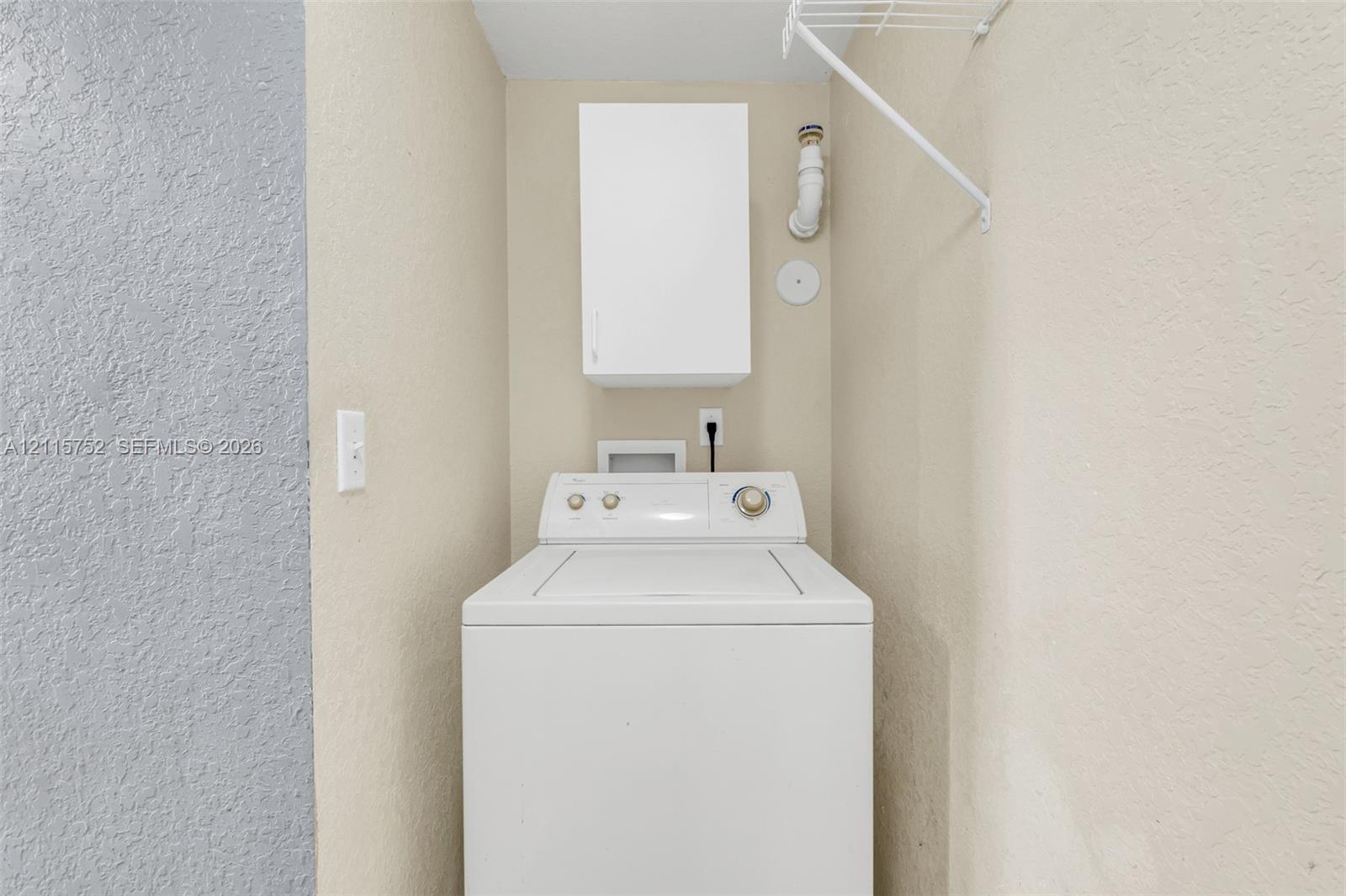 Laundry area featuring a wall-mounted storage cabinet, wire shelving, and dedicated utility hookups