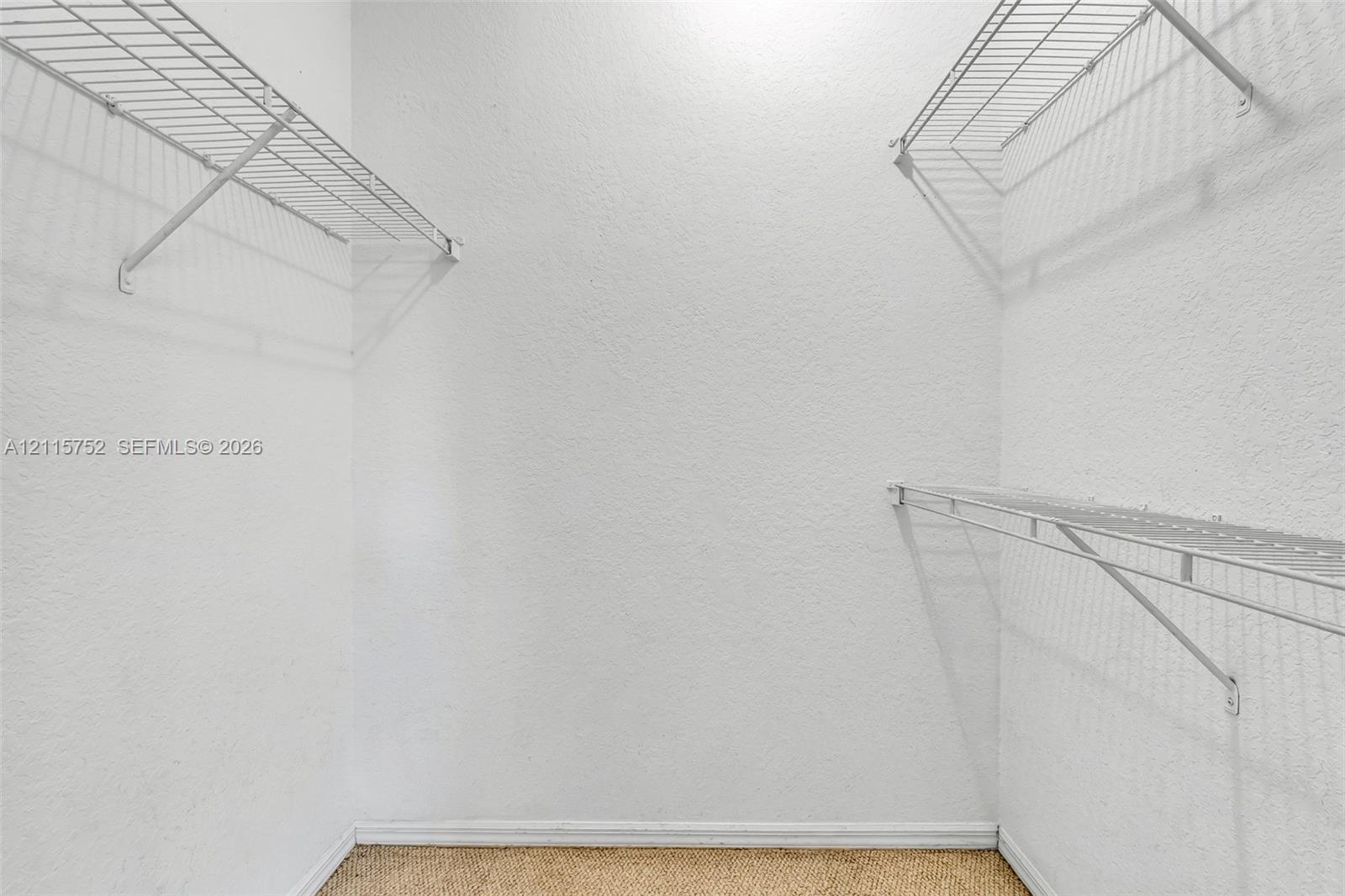 Walk-in closet featuring white walls, textured wall finish, and multi-level white wire shelving