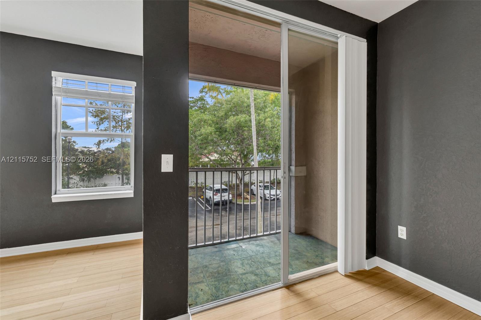 Interior space featuring wood-finish flooring, sliding glass door with balcony access, and single-hung window with a multi-pane upper sash