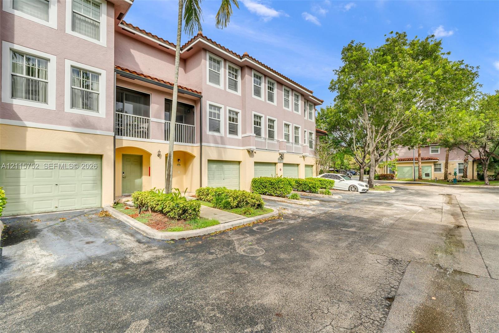 Multi-story exterior featuring a stucco facade, private garage access, second-level balconies, and a tiled roofline Multi-story exterior featuring a stucco facade, private garage access, second-level balconies, and a tiled roofline