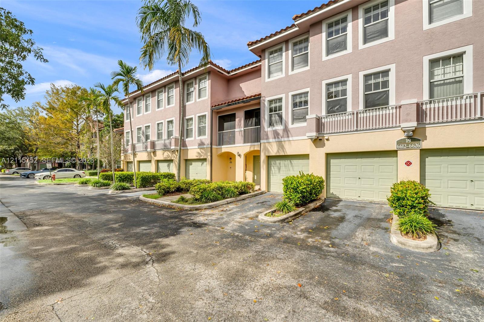 Multi-story stucco exterior featuring tile roofing, individual multi-car garages, private balconies with balustrade railings, and mature palm landscaping Multi-story stucco exterior featuring tile roofing, individual multi-car garages, private balconies with balustrade railings, and mature palm landscaping