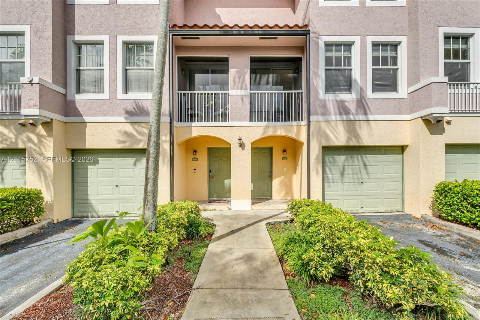Multi-level exterior featuring a stucco facade, private covered balconies with metal railings, and dual attached garages with sectional doors Multi-level exterior featuring a stucco facade, private covered balconies with metal railings, and dual attached garages with sectional doors