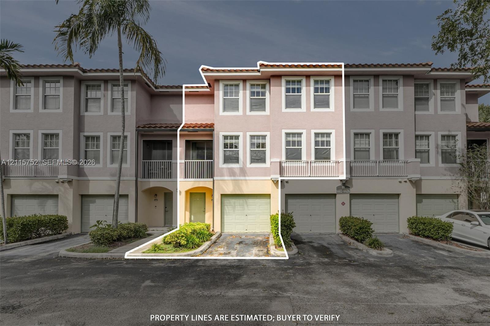 Three-story townhouse exterior featuring a stucco faade, tiled roof, attached garage, and second-level balcony with metal railing Three-story townhouse exterior featuring a stucco faade, tiled roof, attached garage, and second-level balcony with metal railing