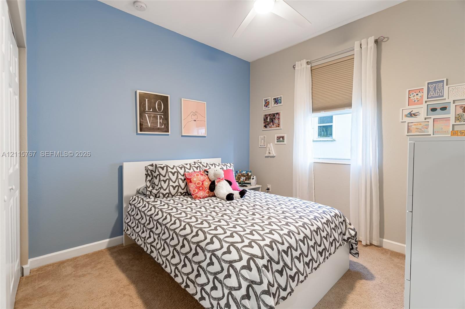 Neutral-toned walls with a blue accent wall, ceiling fan, and carpeting