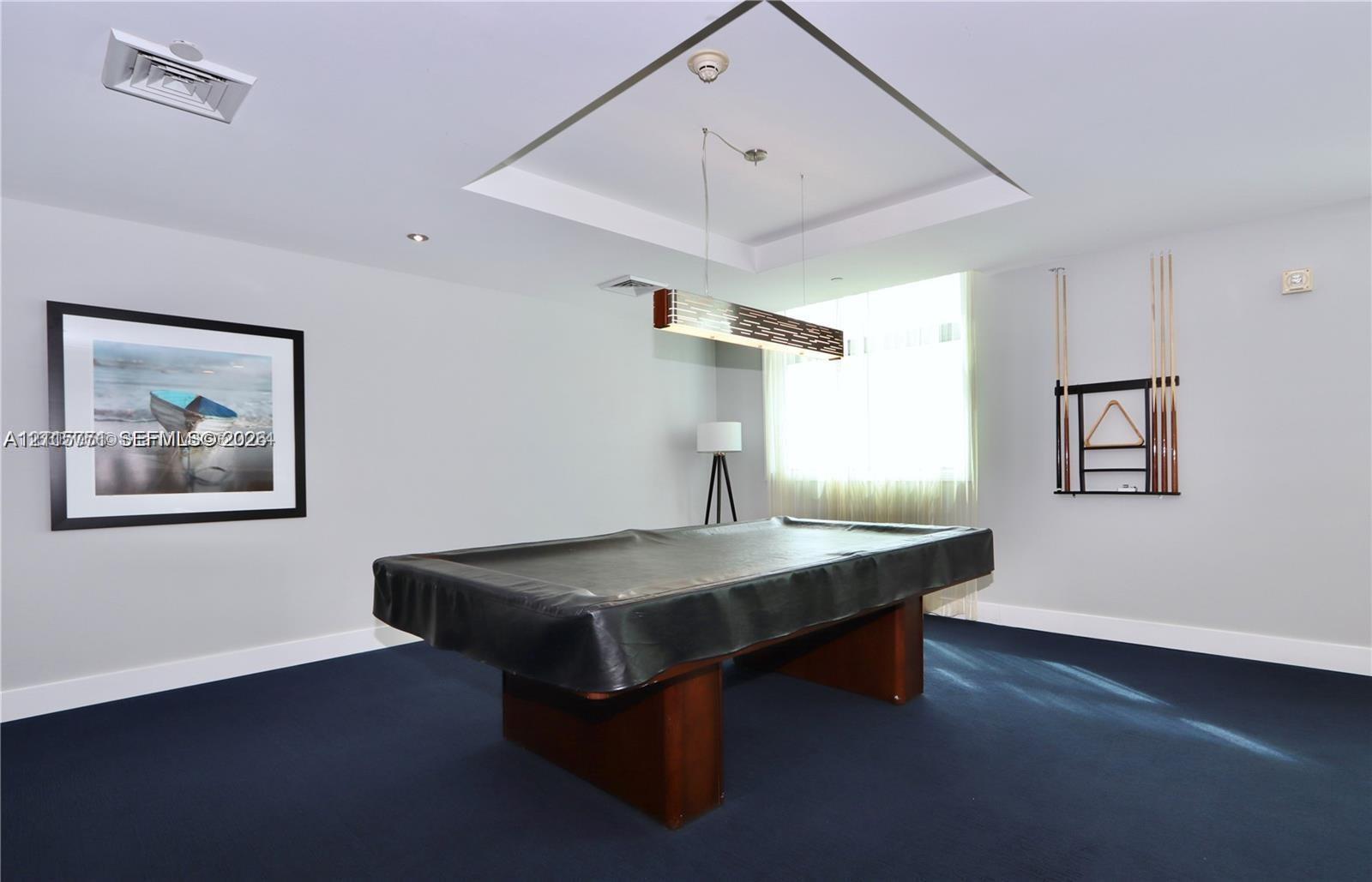 Recessed tray ceiling featuring a linear suspended light fixture and wall-to-wall carpeting