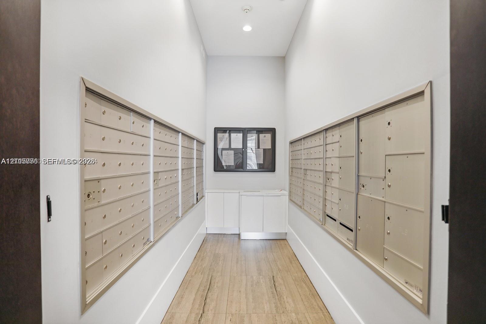 Mailroom featuring multi-tier locking metal mailboxes, wood-finish flooring, recessed lighting, and built-in cabinetry