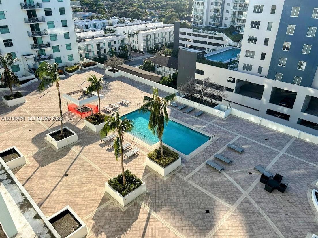 Elevated terrace featuring a rectangular swimming pool, paver-stone decking, and built-in masonry planters with mature palms