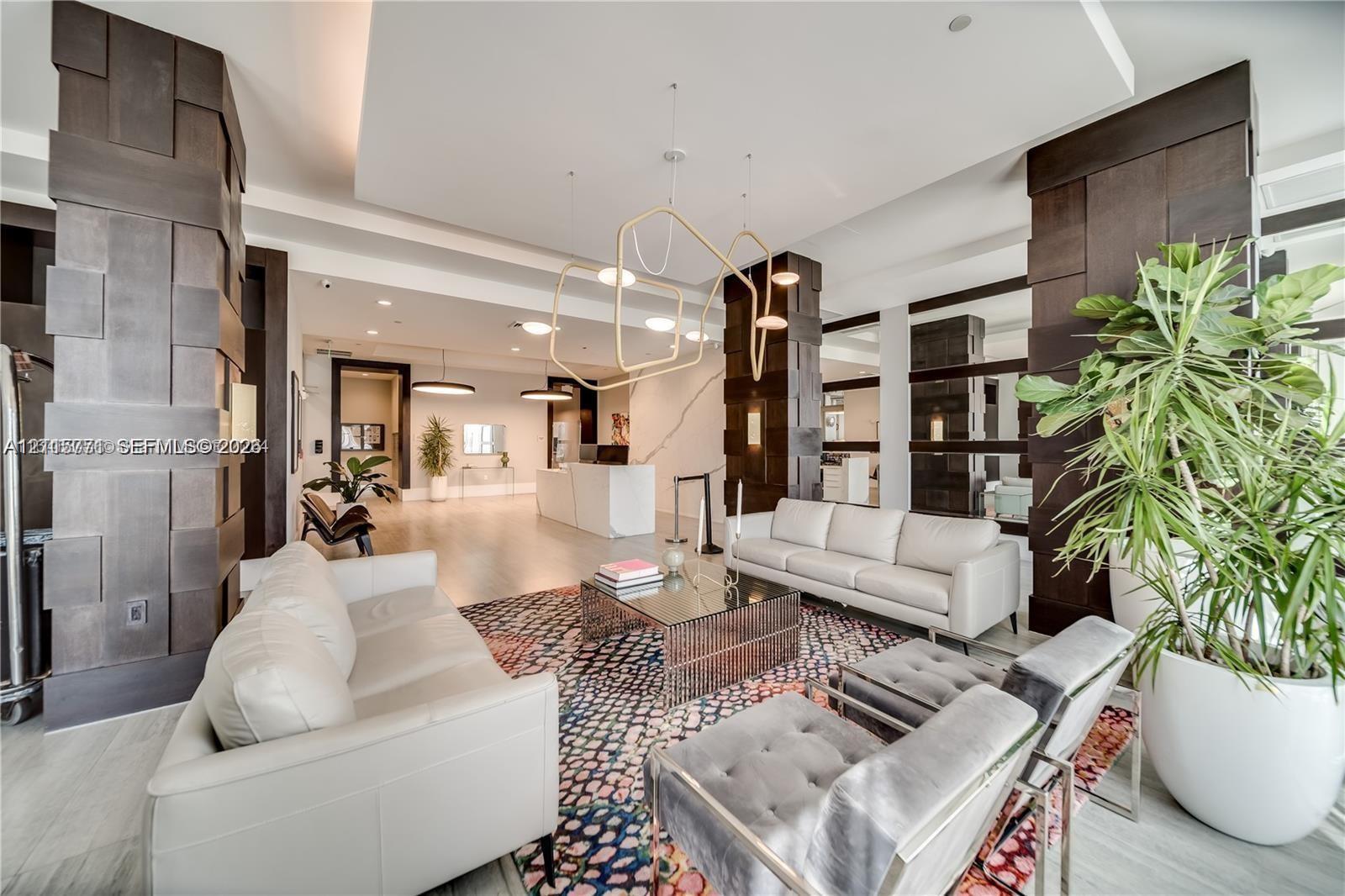 Expansive interior featuring high ceilings, architectural dark wood-paneled pillars, custom geometric pendant lighting, recessed lighting, and stone-finish flooring