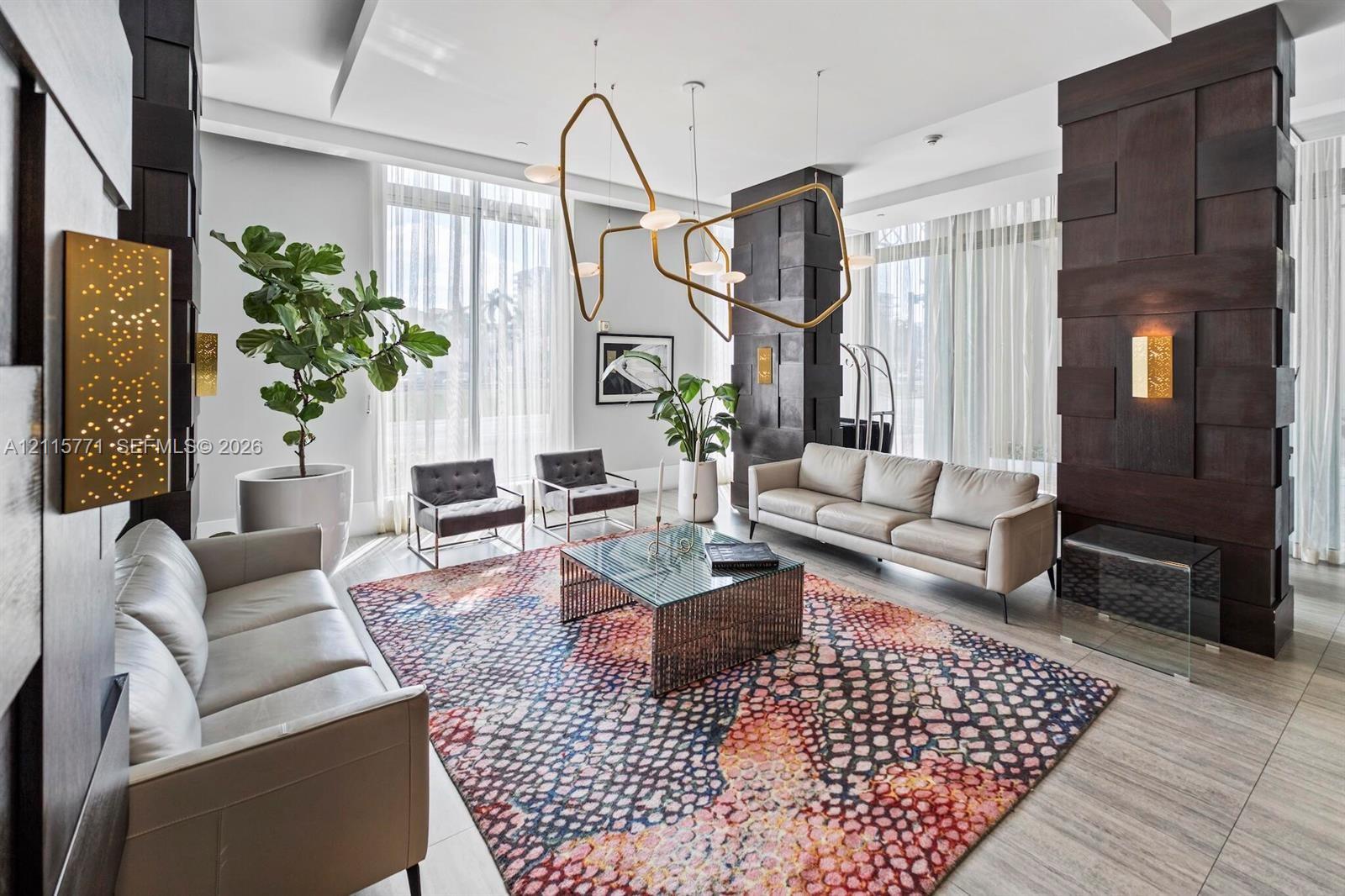 Floor-to-ceiling windows with floor-length drapery, geometric metallic chandelier, tile flooring, and dark wood-finish paneled columns with integrated gold-tone wall sconces