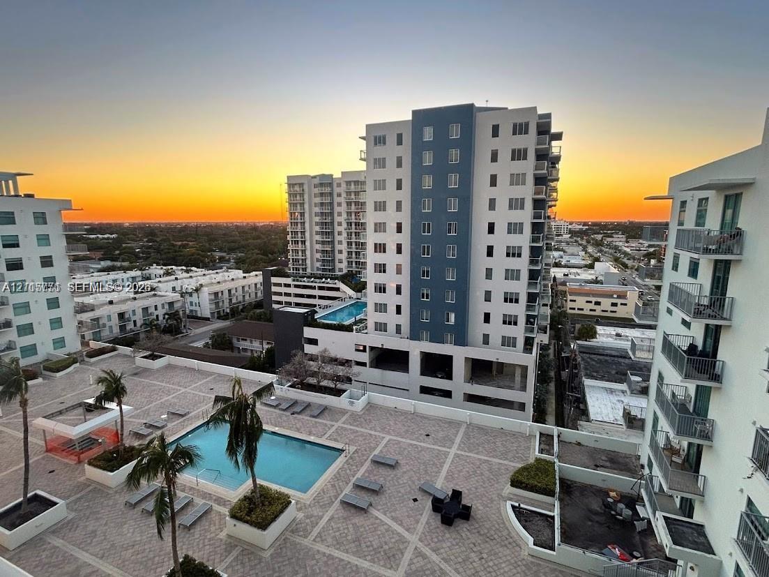 Elevated terrace featuring a paved stone deck, swimming pool, manicured landscaping, and building exterior with private balconies