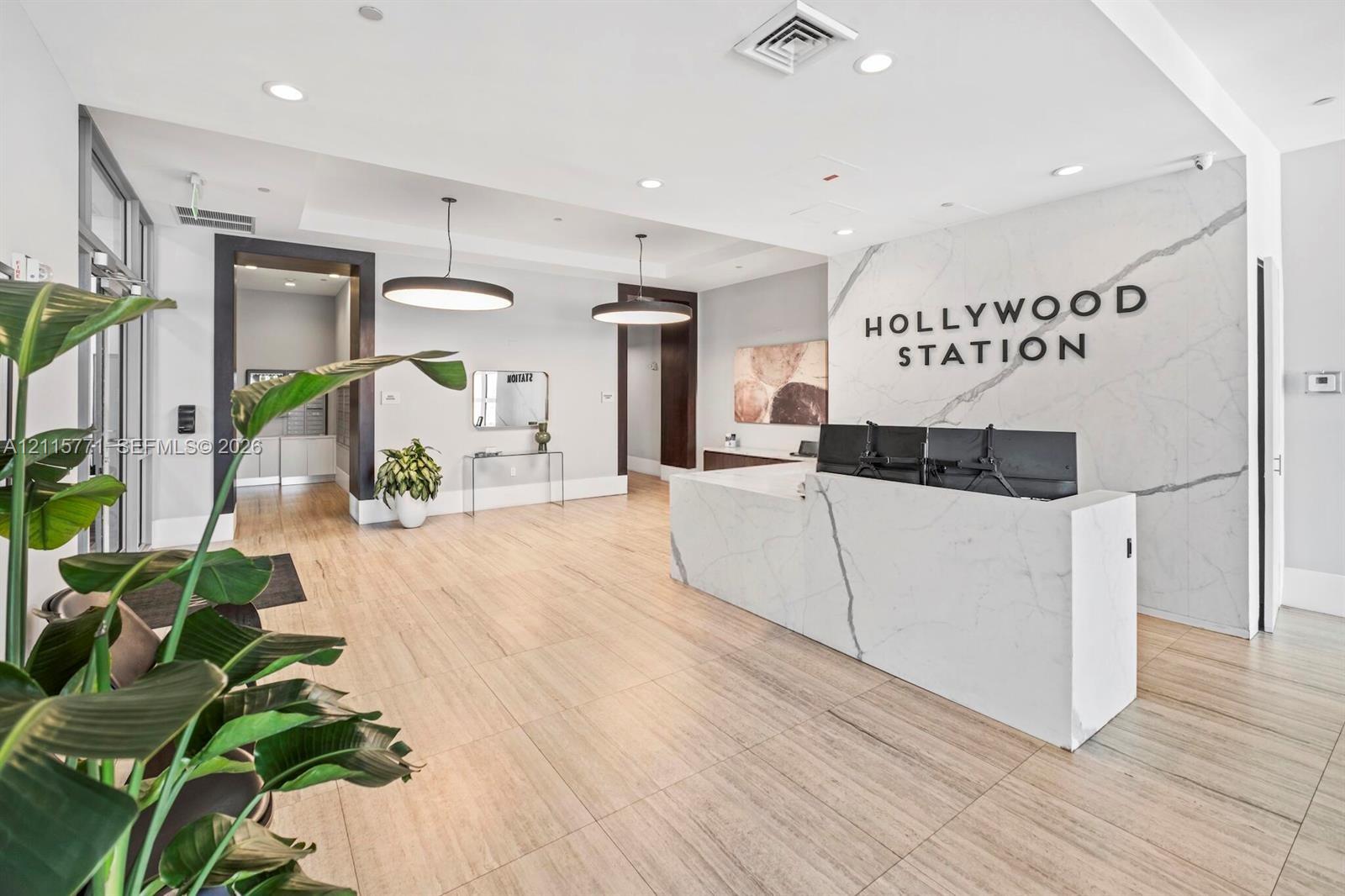 Lobby featuring stone-surround reception desk, wood-finish flooring, recessed lighting, and large pendant light fixtures