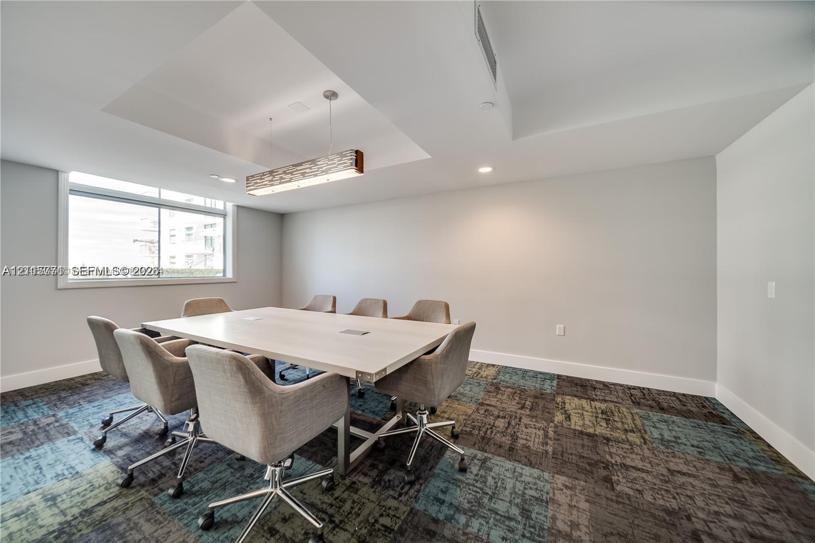Recessed ceiling detail with a linear hanging light fixture, multi-tone patterned carpeting, and large horizontal window