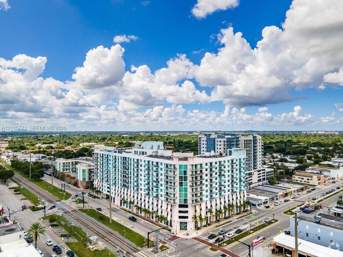 Multi-story residential building featuring a glass facade, private balconies, and ground-level storefronts