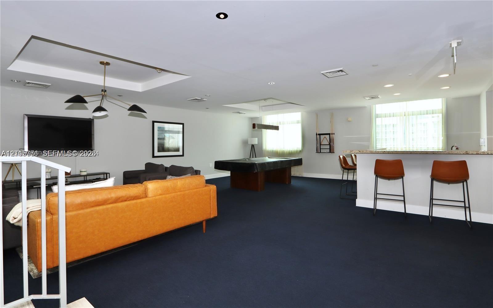 Open-concept room featuring a recessed tray ceiling, multi-arm chandelier, and a built-in counter with a stone surface