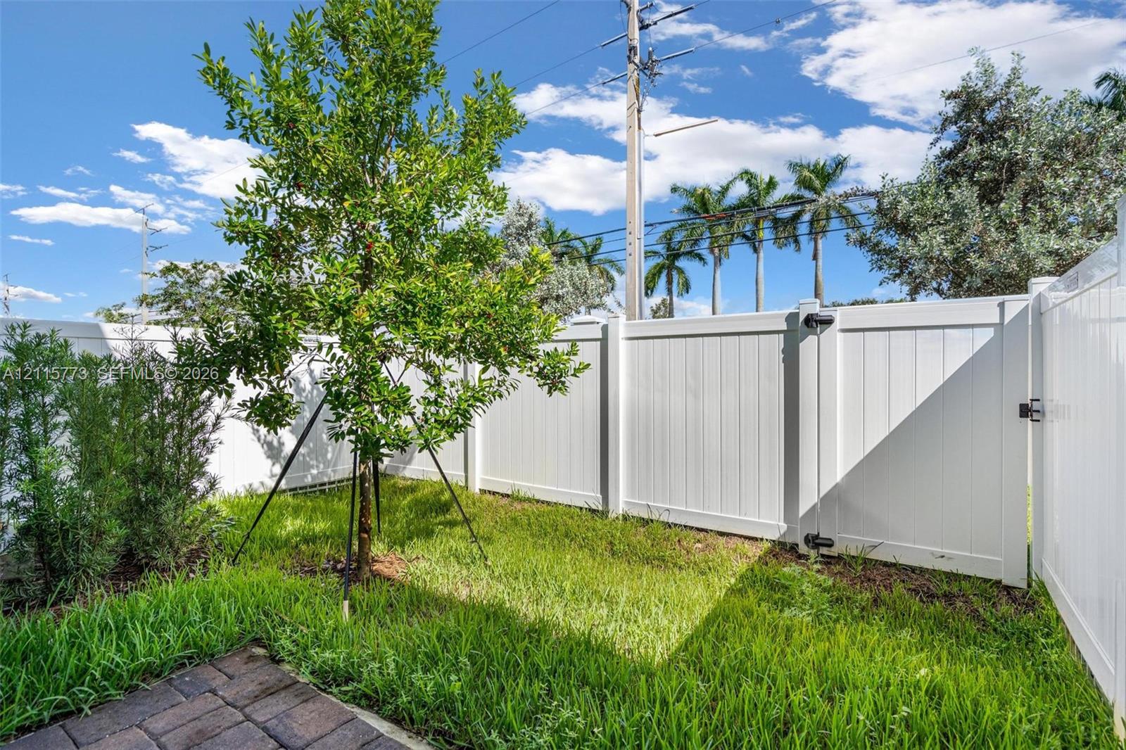 Private outdoor space featuring a white vinyl privacy fence, paver patio, and grass lawn