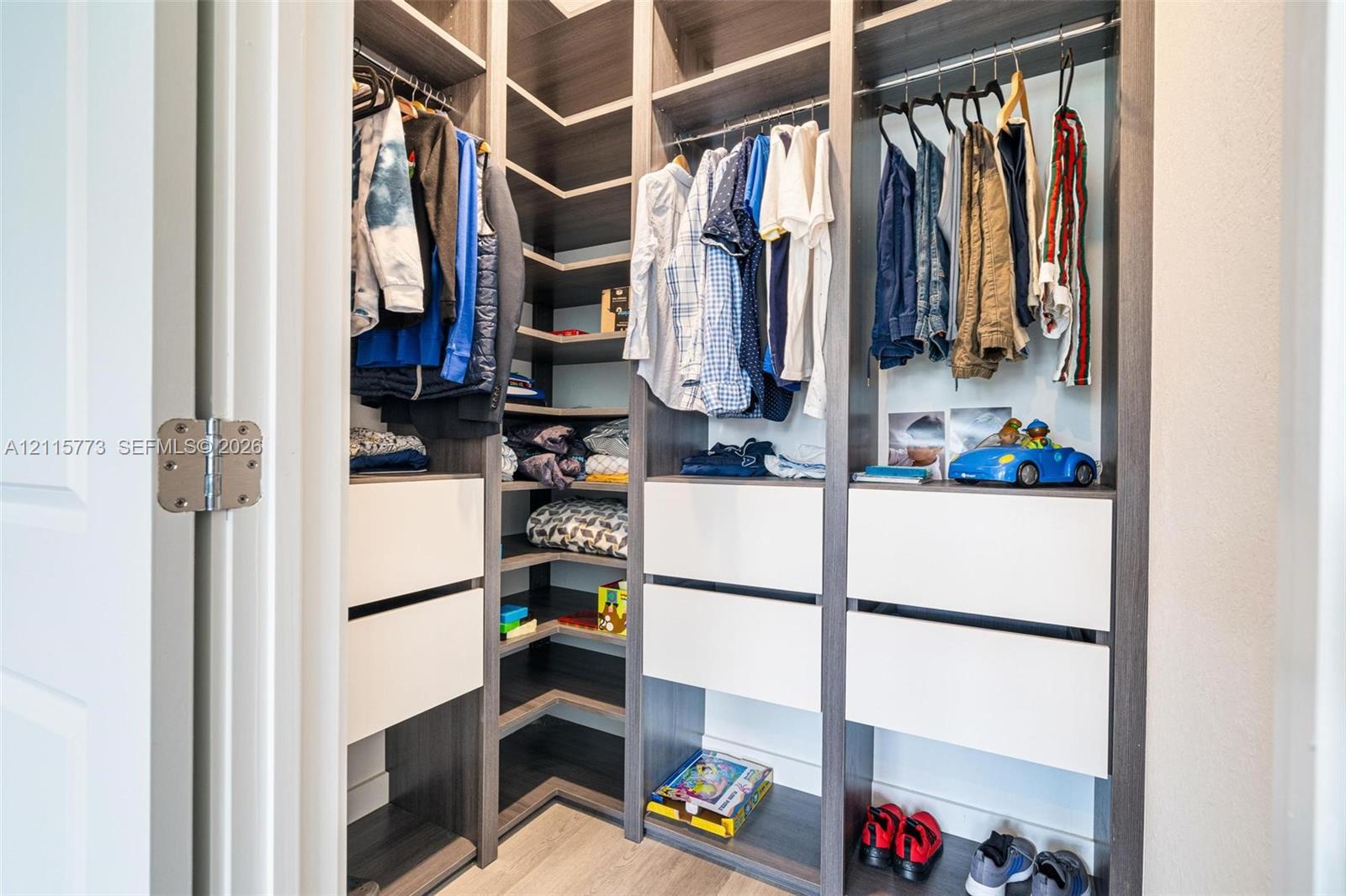 Walk-in closet featuring floor-to-ceiling built-in cabinetry, multi-level hanging rods, corner shelving, and integrated soft-close drawers with a dual-tone wood-finish