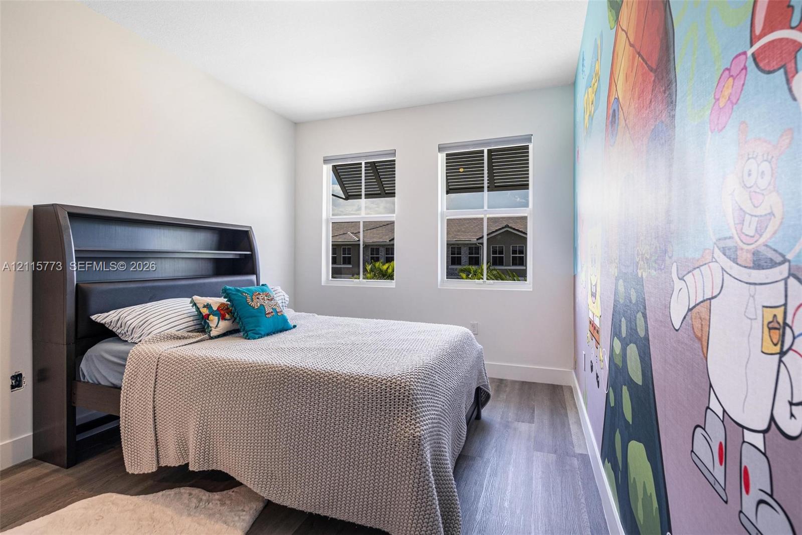 Room featuring two windows, wood-finish flooring, and painted wall mural