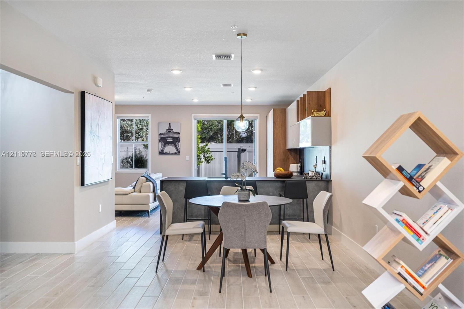 Open-concept kitchen featuring two-toned cabinetry, dark stone-finish countertops, recessed lighting, and wood-finish flooring